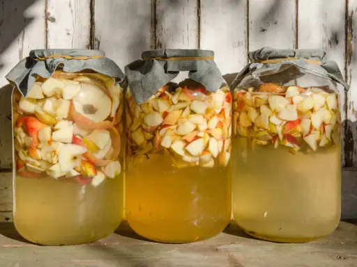 Trois bocaux remplis de pommes coupées, prêts pour la vinaigre de cidre recette de grand-mère.