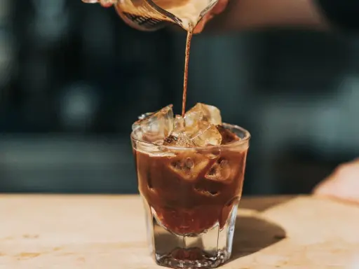 Ein Espresso fließt in ein Glas mit Eiswürfeln. Ist kalter Kaffee gesund? Diese Erfrischung könnte eine Antwort sein.