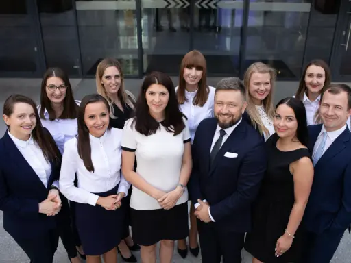 Grupa prawników w garniturach i strojach biznesowych pozuje przed budynkiem.