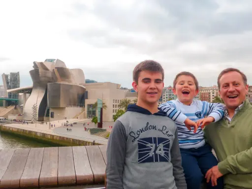 Familia disfrutando de un día en Bilbao con niños, con el icónico Museo Guggenheim de fondo.
