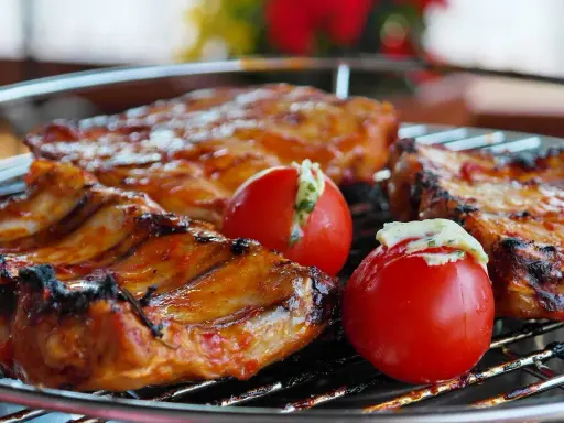 Costillas de cerdo y tomates rellenos en una parrilla. El tiempo que tarda el carbón en hacer brasa es clave para esta deliciosa cocción.