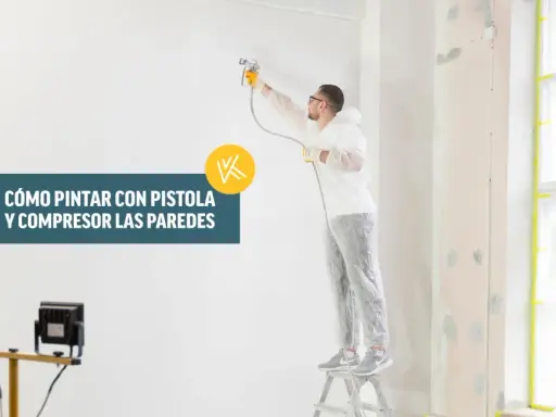 Hombre con traje protector pintando una pared con pistola y compresor.