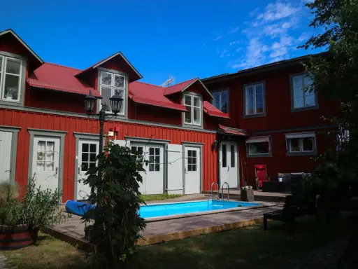 Rött hus med vita fönsterluckor och en blå pool. Kanske finns det tre små rum därinne, redo för gäster.