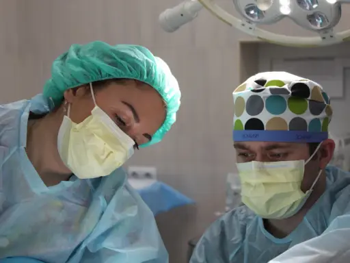 Chirurdzy w maskach i czepkach analizują sytuację po laserowym usunięciu prostaty, rozważając potencjalne powikłania.