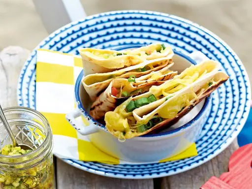 Leckeres Quesadillas Rezept: goldbraune Tortillas gefüllt mit geschmolzenem Käse und Frühlingszwiebeln, serviert in einer Schüssel.