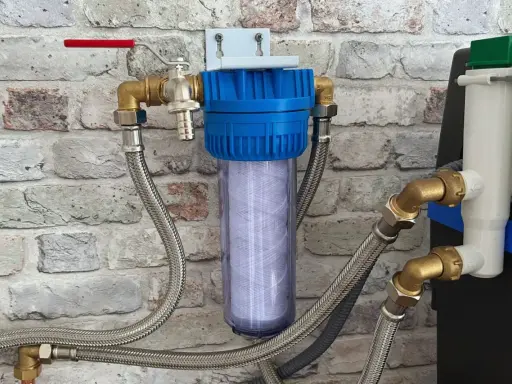 Système de filtration d'eau avec cartouche visible, raccordé à un adoucisseur. Un filtre avant adoucisseur obligatoire pour une eau pure.