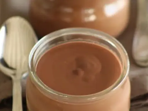 Un pot de crème chocolat onctueuse, prêt à être dégusté avec une cuillère.
