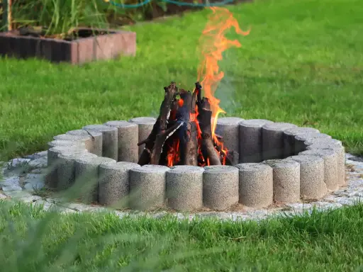 Eine Feuerstelle mit gemauerten Steinen und loderndem Feuer im Garten.