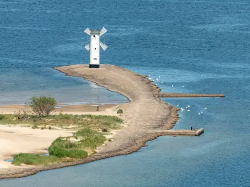 Latarnia morska w kształcie wiatraka, idealne miejsce na wakacje w Polsce. Widok na morze, plażę i ławicę z łabędziami.