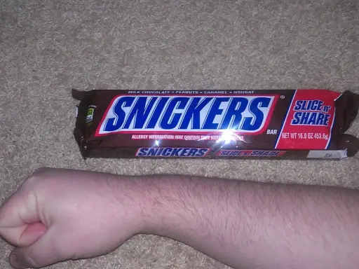 Opakowanie Snickers Slice 'n Share, obok ludzkiej ręki. Zastanawiasz się, snickers ile kalorii?