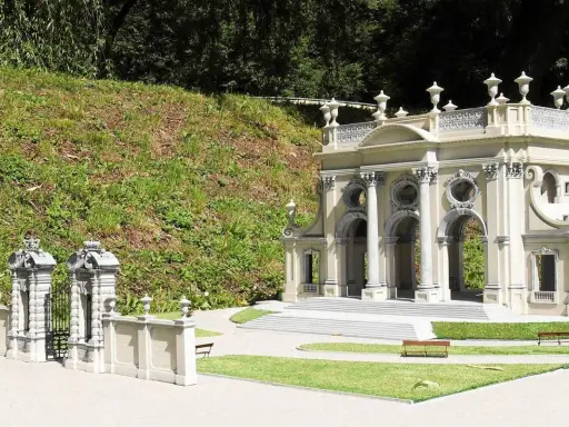 Miniaturowa budowla z kolumnami i bramą, jak w parku miniatur województwa mazowieckiego.