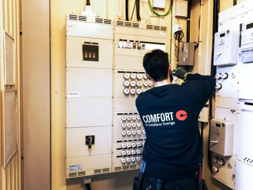 En elektriker arbetar vid en elcentral med många säkringar och mätare. För säkerheten måste man ha jordfelsbrytare.