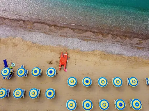 Ombrelloni blu e gialli e una barca rossa sulla spiaggia di Misano Marittima, con il mare turchese sullo sfondo.