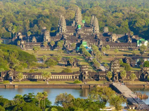 Majestatyczna świątynia Angkor Wat w Siem Reap, otoczona bujną zielenią, z mostem i jeziorem w tle.