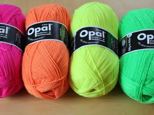 Four balls of Opal yarn in bright pink, orange, yellow, and green.