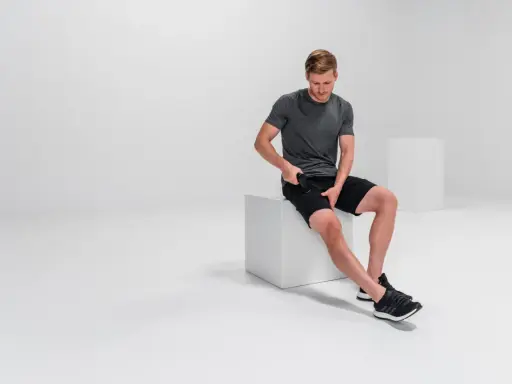 Mann massiert mit Massagepistole seine Oberschenkel, um adduktoren schmerzen zu lindern.