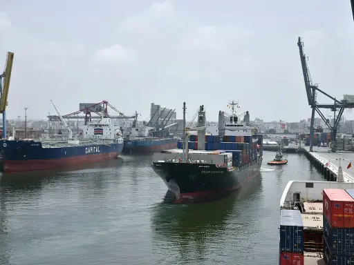 Navi da carico e gru nel porto di Casablanca. Un rimorchiatore assiste una nave portacontainer.