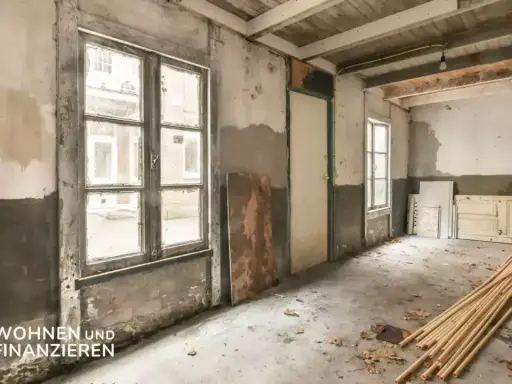 Renovierungsbedürftiger Raum mit alten Fenstern und Türen. Hier werden die **kernsanierung kosten** sichtbar.