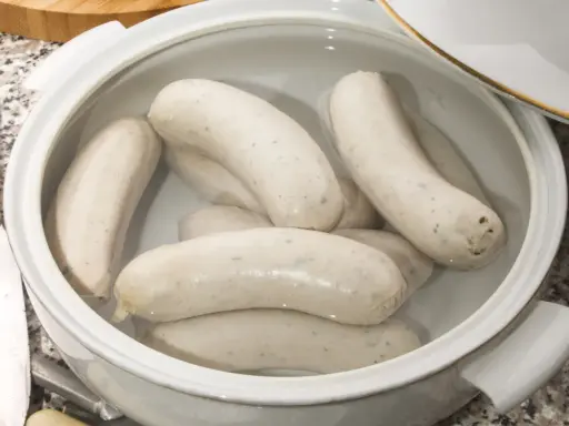 Biała kiełbasa w garnku z wodą, gotowa do parzenia. Idealny sposób, jak sparzyć białą kiełbasę, by była soczysta i smaczna.