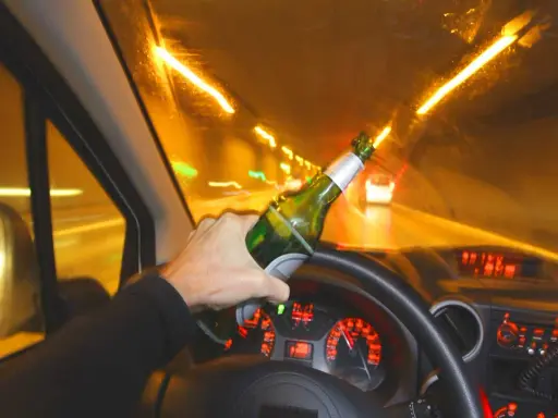 Ręka trzymająca butelkę piwa za kierownicą. Widok z wnętrza samochodu jadącego nocą. Stan nietrzeźwości, ile promili?