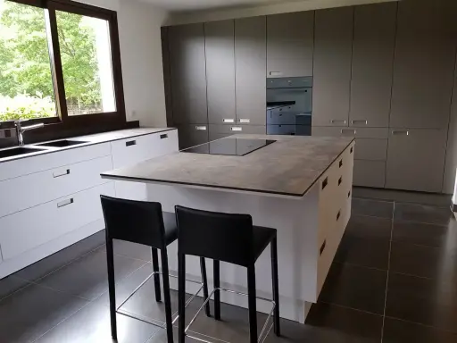 Cuisine moderne avec îlot central. On peut facilement faire le tour de cet îlot central pour accéder aux plans de travail et aux tabourets.