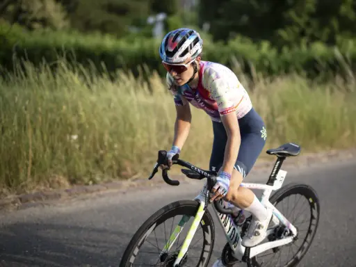 Elise Chabbey in voller Fahrt auf ihrem Rennrad, die Konzentration im Blick, während sie durch eine grüne Landschaft fährt.