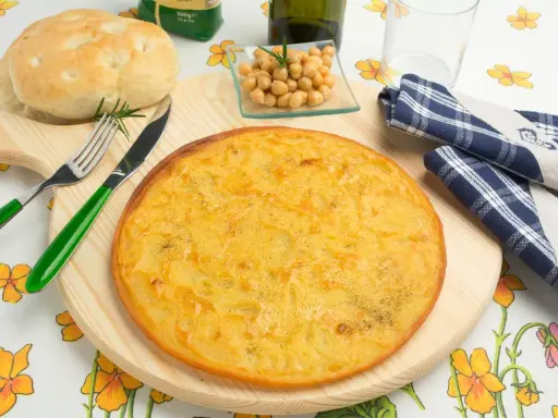 Una gustosa farinata di ceci in padella, pronta per essere gustata con pane fresco e un rametto di rosmarino.