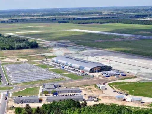 Lotnisko Warszawa Modlin z lotu ptaka: nowoczesny terminal, pas startowy i rozległe tereny zielone.