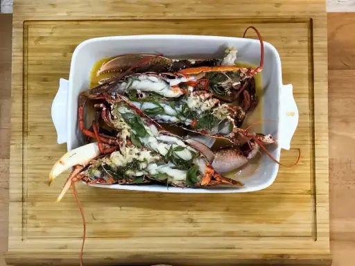 Homards bleus préparés dans un plat blanc, prêts pour une recette savoureuse.