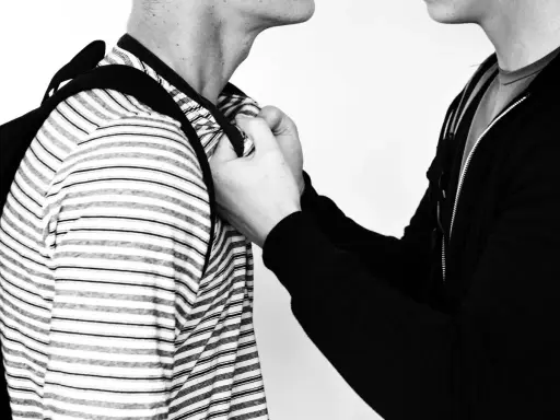 Due persone, una con una felpa nera, afferra l'altra per il colletto. Un'immagine che evoca la psicologia delle persone aggressive.
