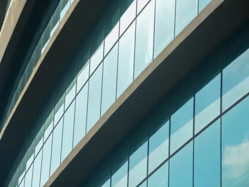 Fachada de edificio moderno con paneles de cristal azul que reflejan el cielo. El **solar glass** captura la luz del sol para generar energía.
