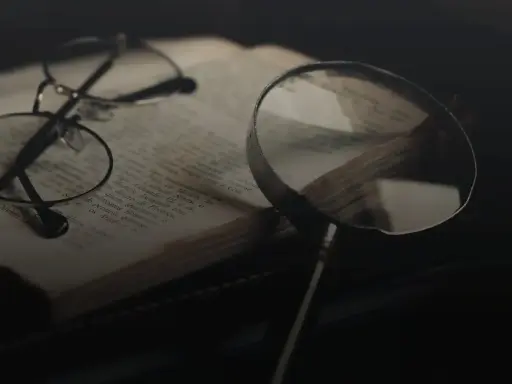 Brille und Lupe über einem alten Buch, bereit für eine tiefgehende Gedichtanalyse.