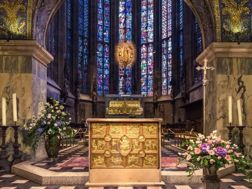 Wnętrze katedry z ołtarzem i witrażami. Wzrok przyciąga złota szkatuła, przypominająca o treści psalmu 137.