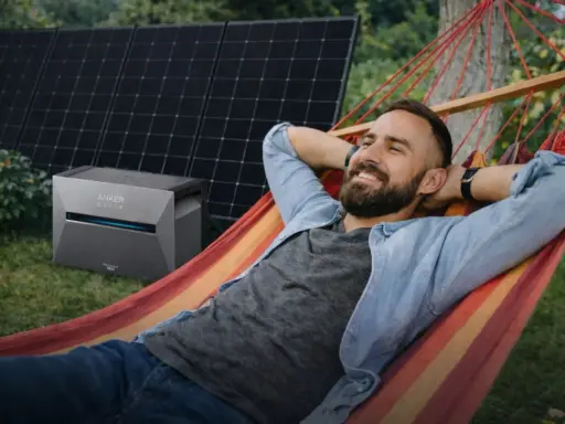 Mann entspannt in Hängematte, daneben Balkonkraftwerk Niedersachsen mit Solarmodulen.