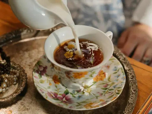 Té floral servido en una taza decorada, perfecto para celebrar los 20 años de casados. Un detalle de joyas antiguas añade elegancia.