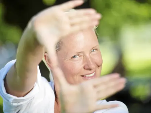 Regina Lund ler inramad av sina händer, som om hon skapar en scen för en film.