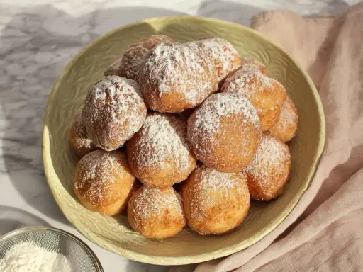 Stosik pysznych, puszystych pączków posypanych cukrem pudrem. Idealne na tłusty czwartek, te fit pączki wyglądają apetycznie.