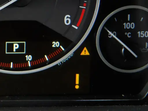 Na desce rozdzielczej świeci żółty trójkąt z wykrzyknikiem, sygnalizując problem. Obok wskaźnik temperatury silnika.