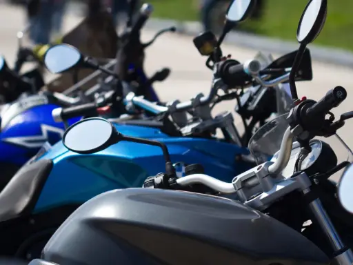 Manillar de moto con espejos y parte del depósito. Un carnet de moto a punto de ser usado.