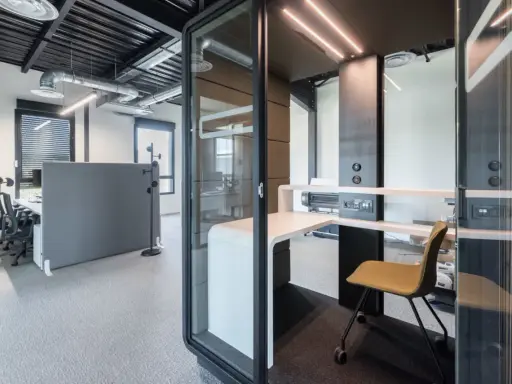 Un bureau moderne avec des cabines acoustiques et du mobilier flex office, idéal pour la concentration.