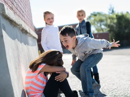 Niña acosada por otros niños en la calle.