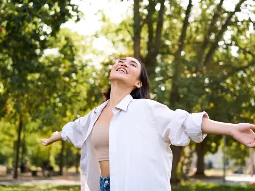 Jeune femme rayonnante dans un parc, profitant de la nature. Elle semble ressentir les bienfaits de la L-tyrosine pour son bien-être.