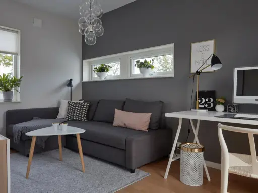 Snyggt hemmakontor med mörkgrå vägg, soffa, skrivbord och dator. Inspiration för ett modernt och stilrent arbetsrum.