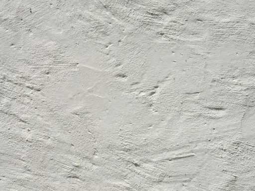 Texture d'enduit à la chaux blanc, présentant des irrégularités et des taches subtiles, témoignant de son application manuelle.