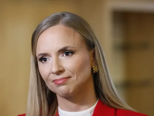 Sara Skyttedal, med sitt blonda hår och röda kavaj, ler snett mot kameran.