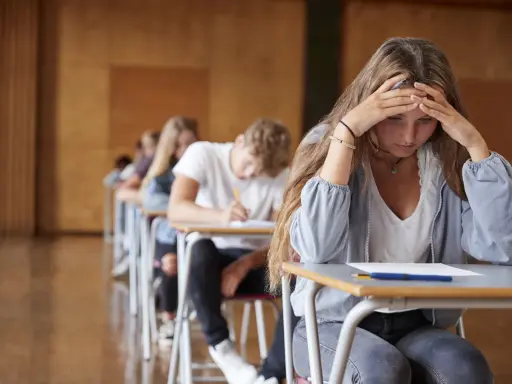 En tjej med händerna mot pannan känner efter studenten ångest under ett prov.