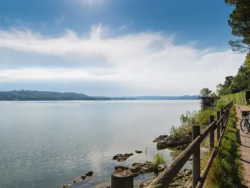 Ciclista ammira un lago in Lombardia, godendosi una delle tante ciclabili panoramiche.