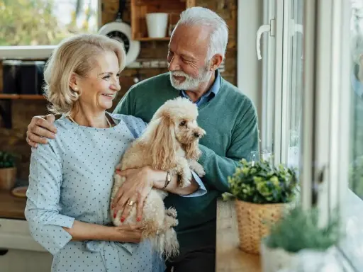 Uśmiechnięta para seniorów trzyma pudla. Idealny pies dla seniora, który wnosi radość i towarzystwo.