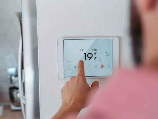 Main d'une personne ajustant la température sur un écran tactile, optimisant la programmation chauffage pour un confort idéal.