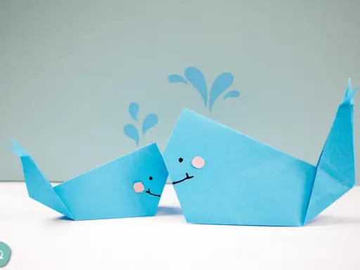 Zwei niedliche Origami-Wale, die Wasser spritzen.